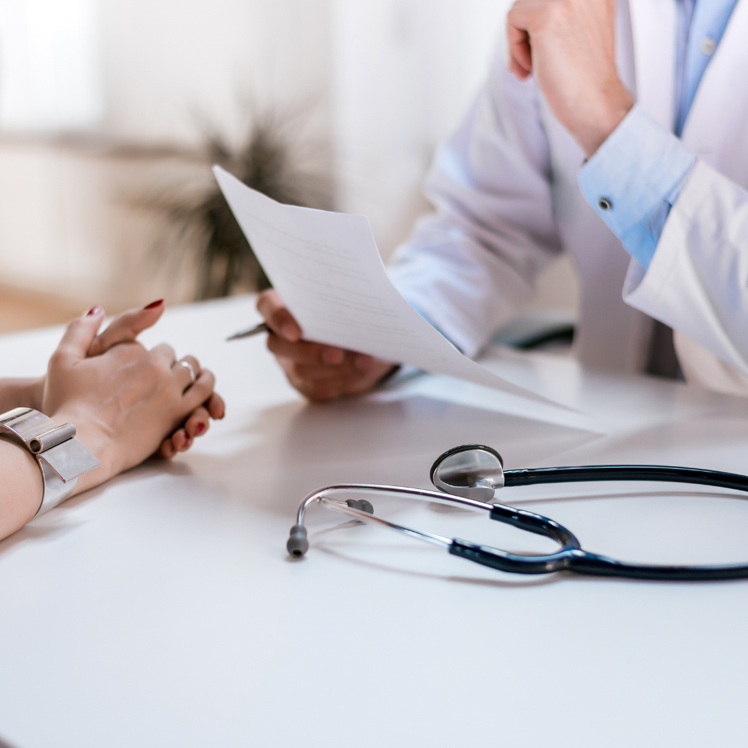 A doctor is talking to a patient while holding a piece of paper.