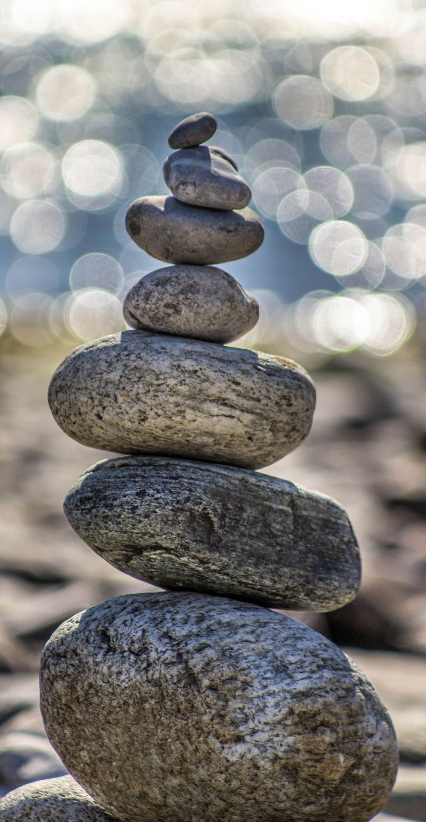 Stacked stones on a beach with blurred ocean bokeh in the background