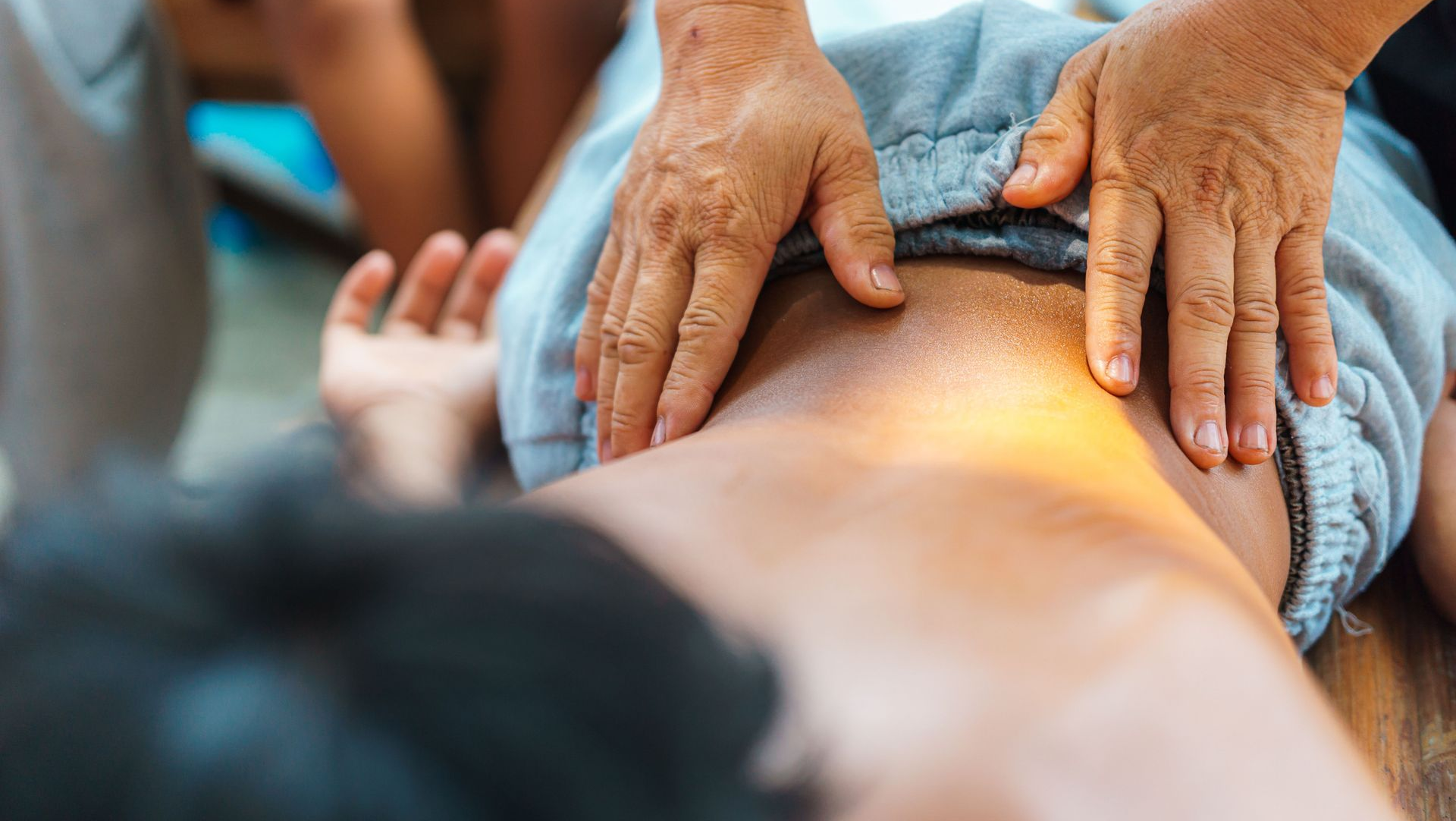 Hands massaging a person’s lower back during a therapeutic treatment