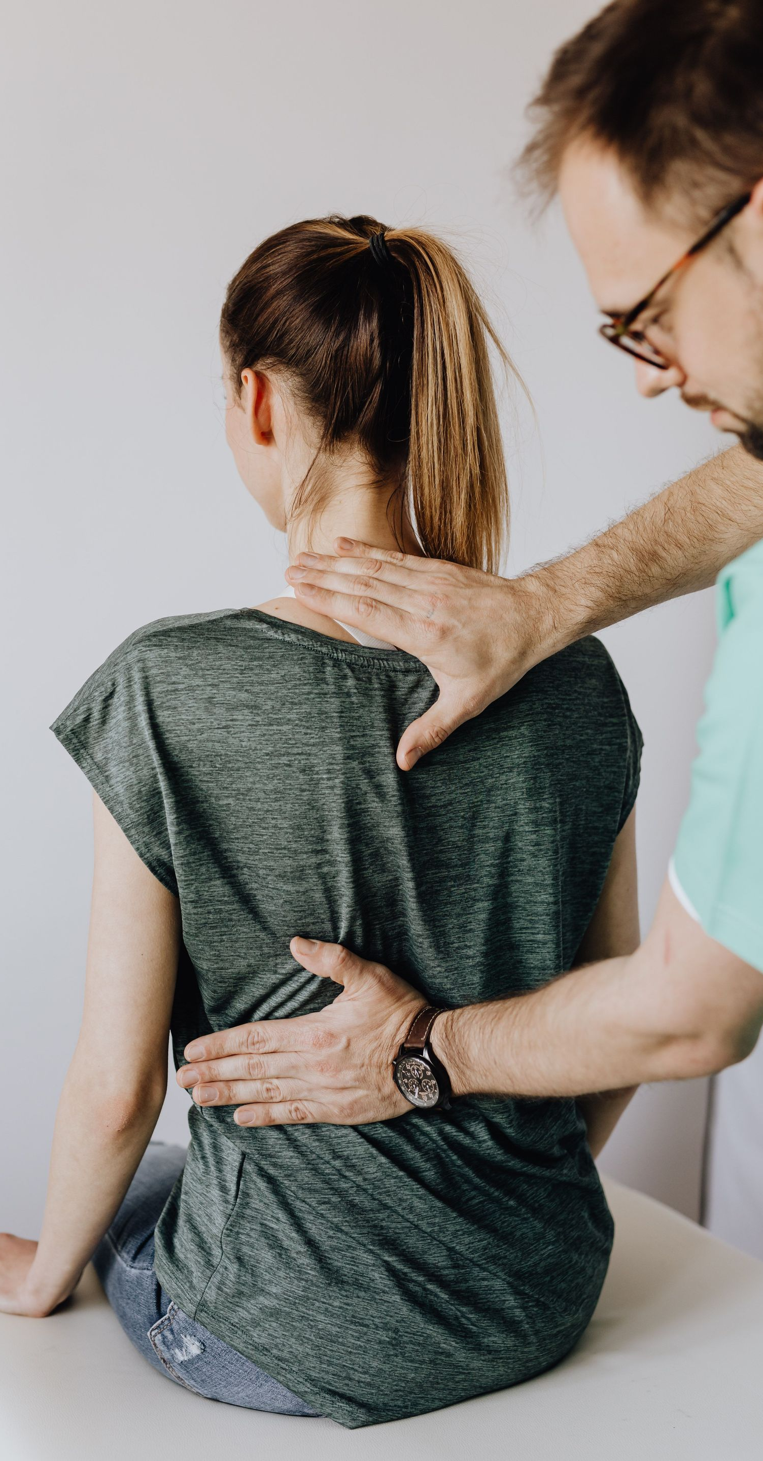 Therapist massaging a seated person’s back and shoulder in a clinic setting