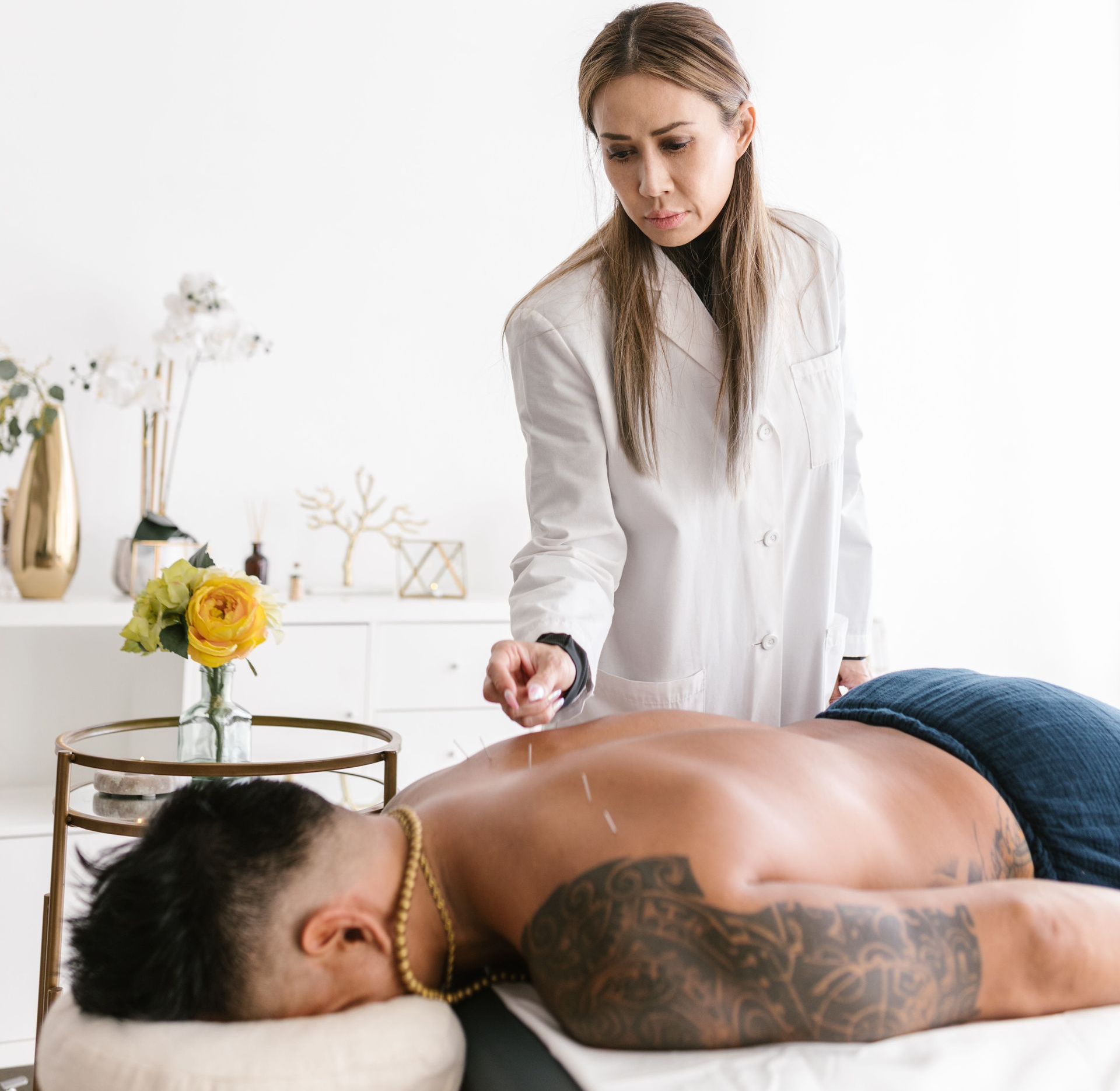 Massage therapist applying back treatment to a client on a table in a bright spa room