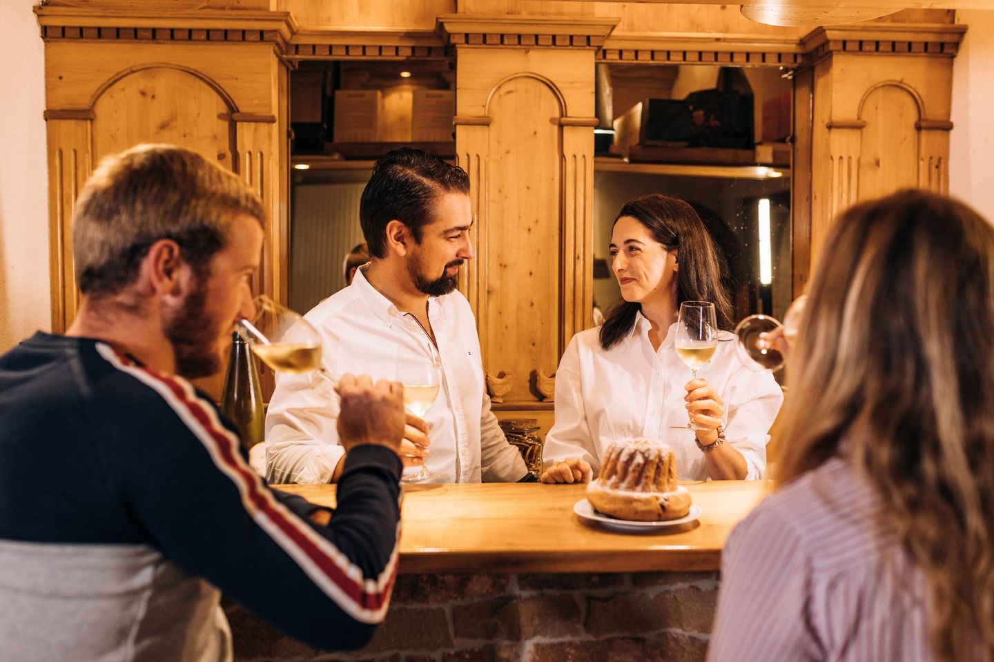 Un groupe de personnes est assis à un bar en train de boire du vin.