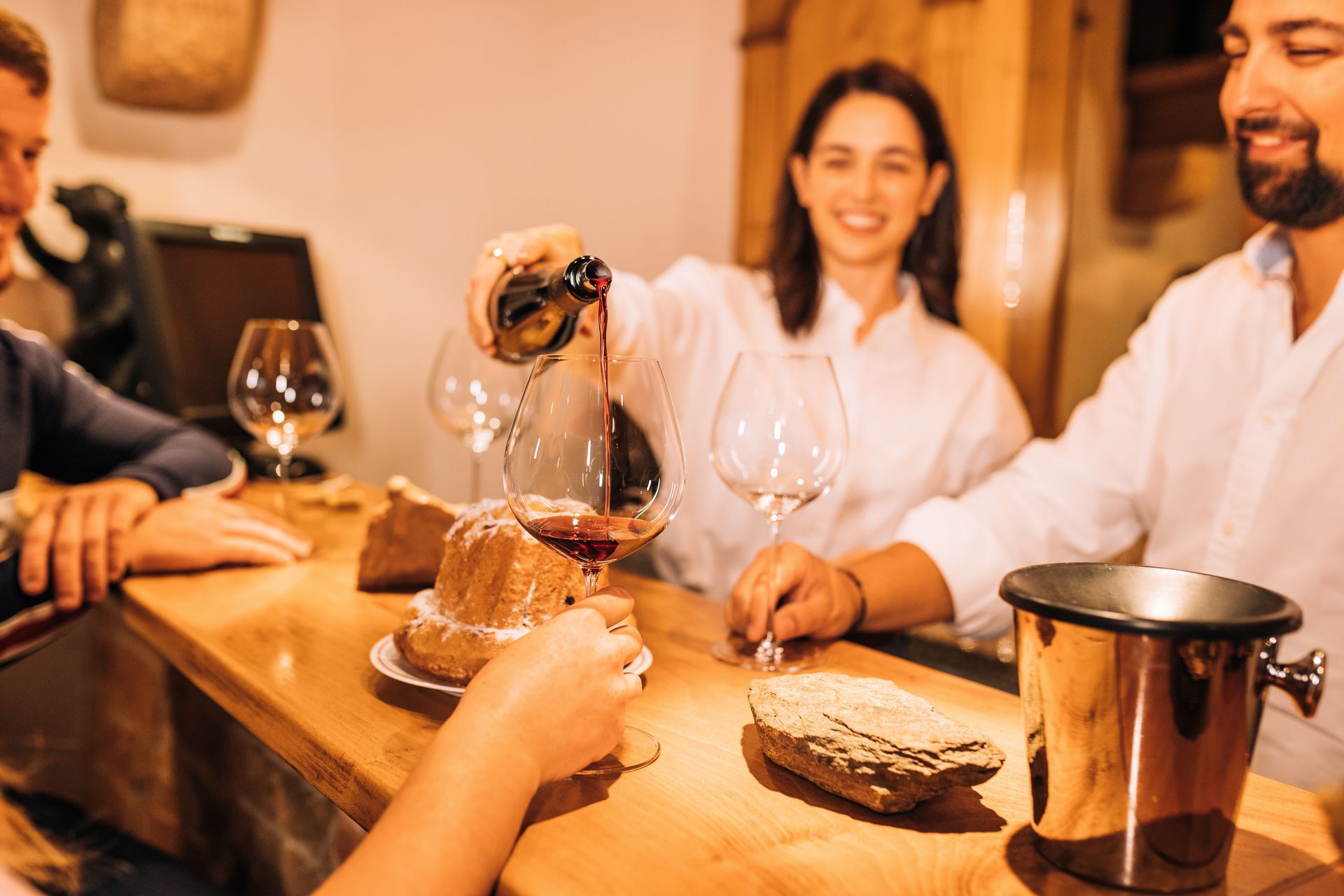 Un groupe de personnes est assis à une table en train de boire du vin.