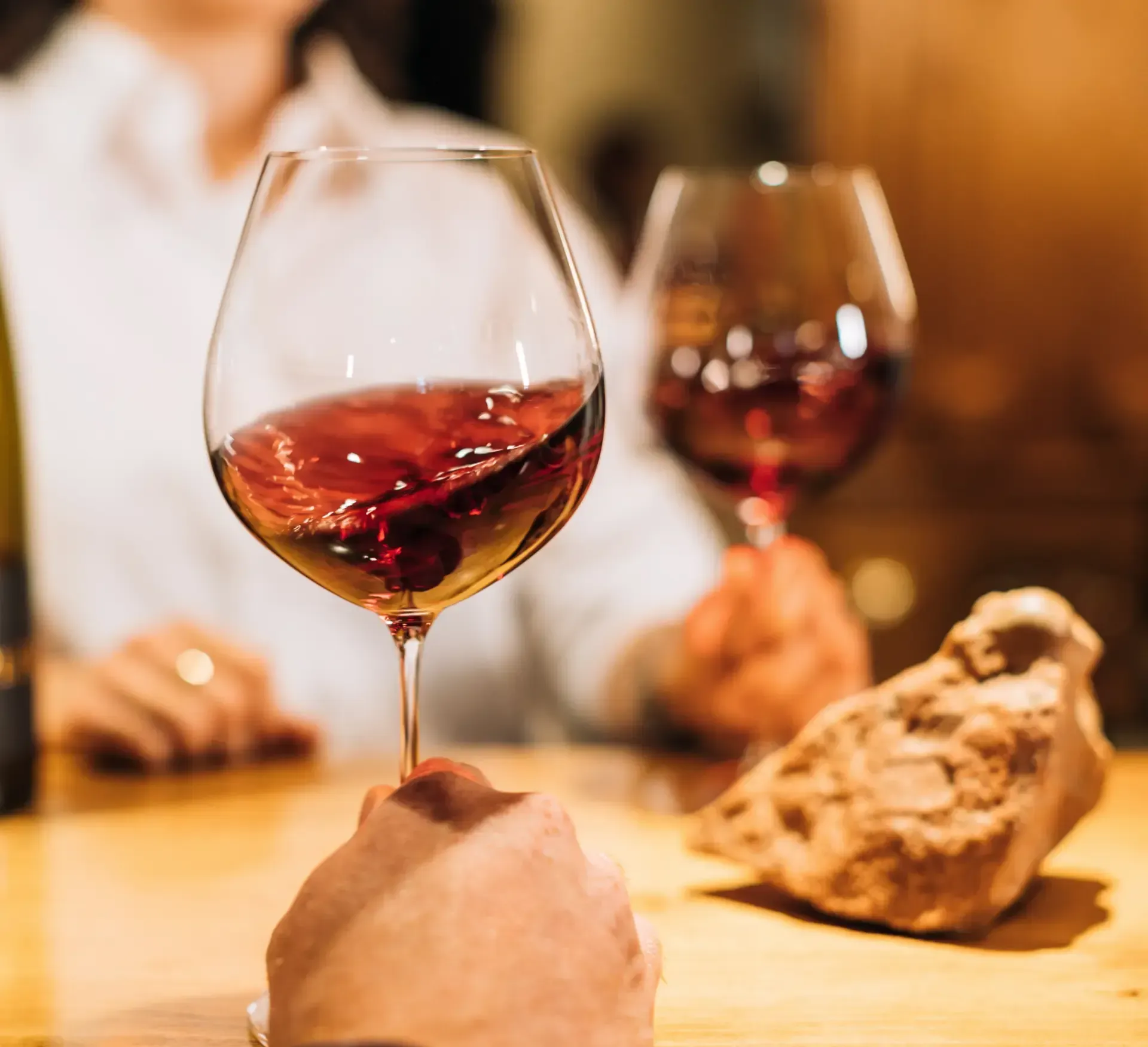 Une personne tient un verre de vin rouge sur une table
