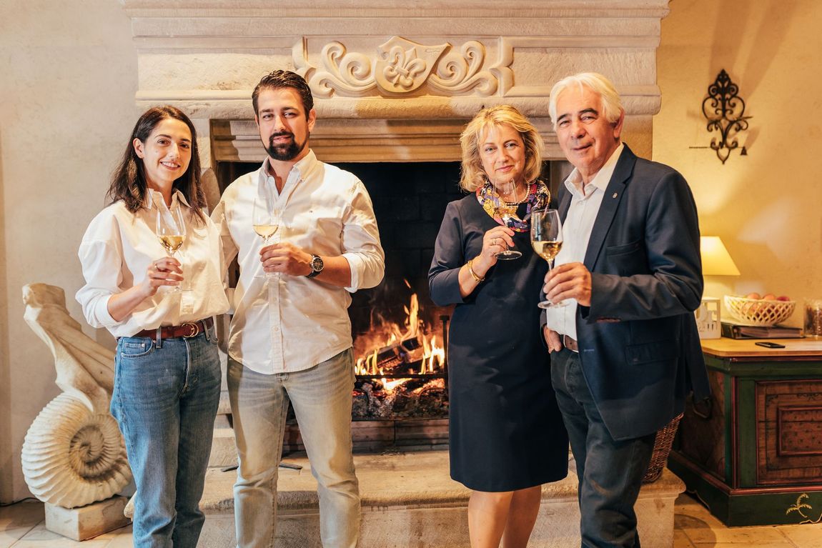Un groupe de personnes se tient devant une cheminée tenant des verres à vin.