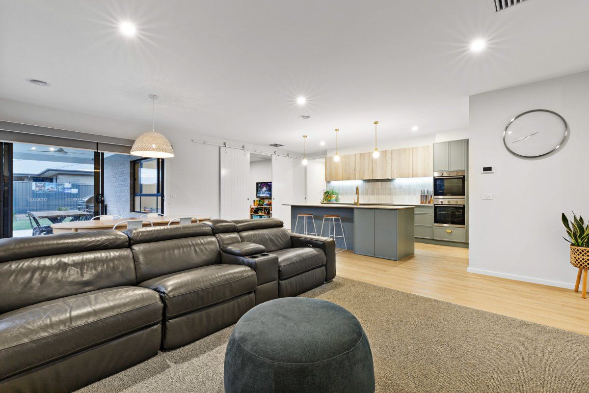 A Living Room With A Couch, Ottoman, And A Kitchen In The Background — Jetsonian Constructions In Wendouree, VIC