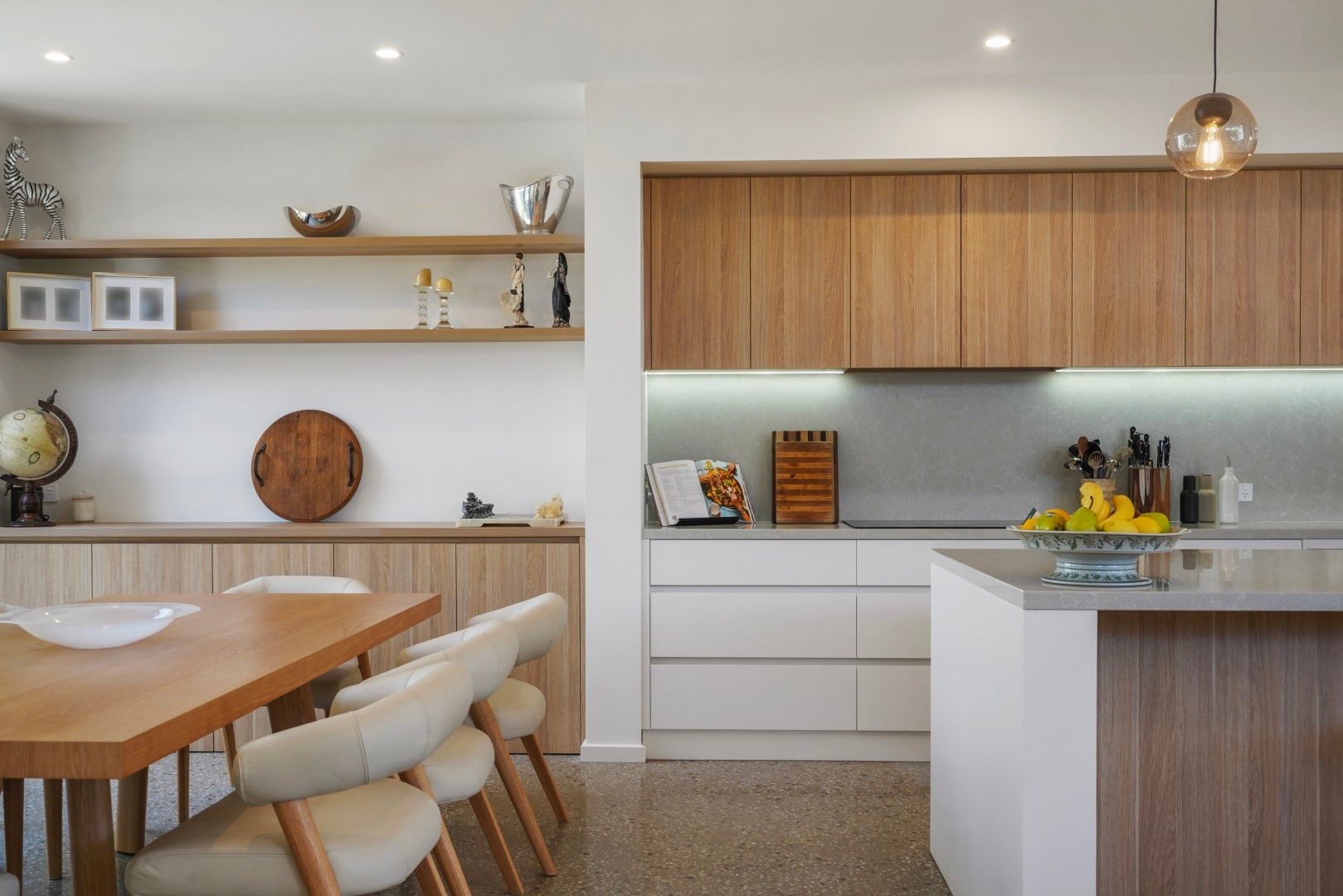 Modern Kitchen With Wood Cabinets, White Island, Dining Table, and Open Shelves in a Bright Interior — Jetsonian Constructions In Wendouree, VIC
