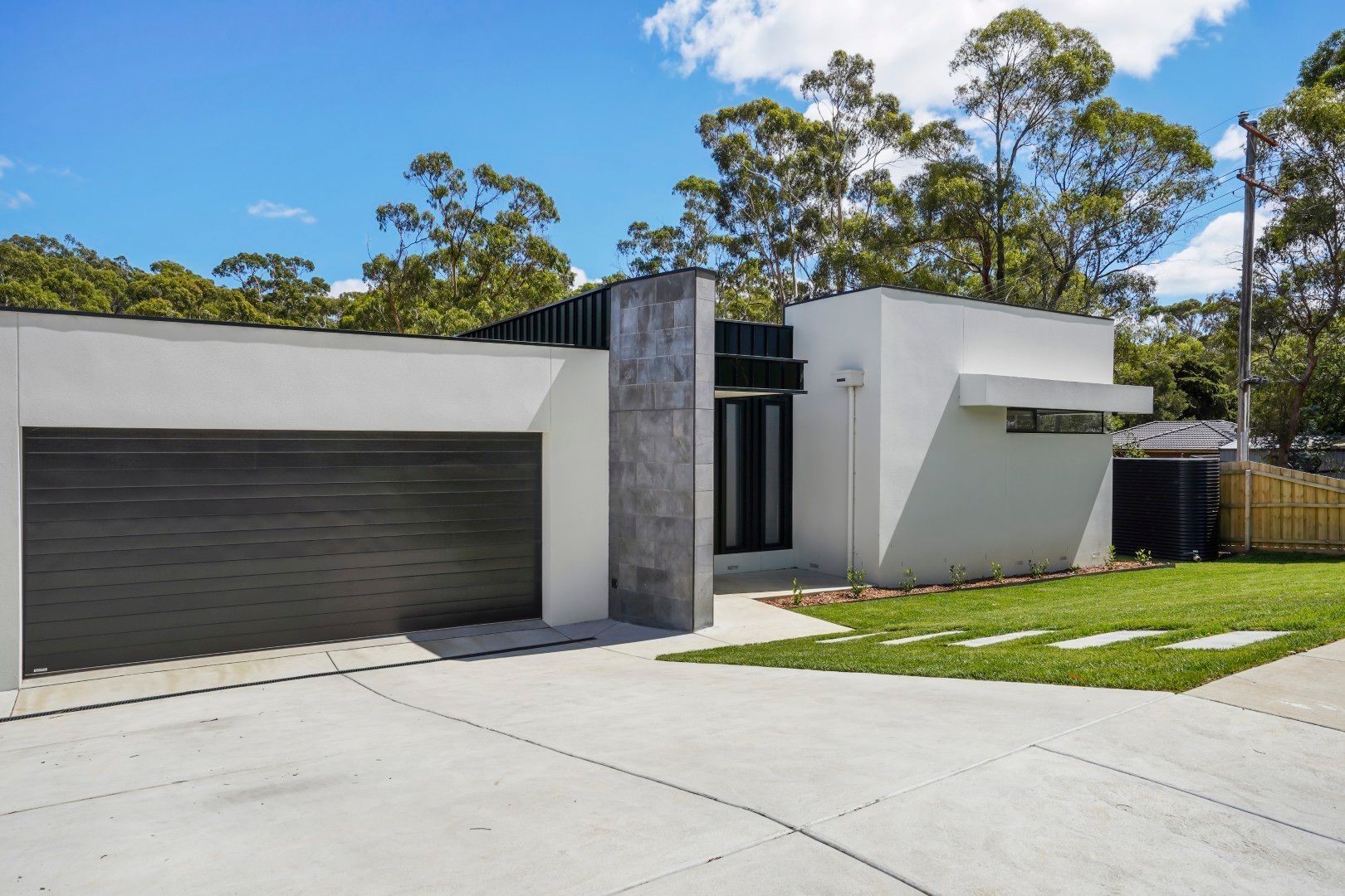 Modern White House With Black Garage Door and Slanted Roof in a Sunny Suburban Setting — Jetsonian Constructions In Wendouree, VIC