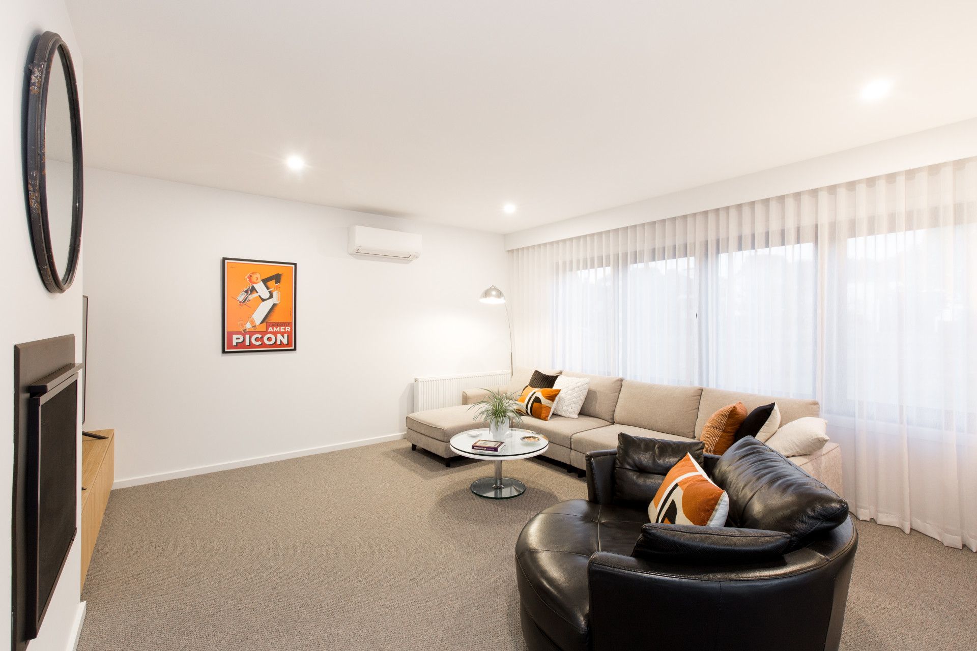 Bright modern living room with gray sofa, black chair, coffee table, wall art, and large sheer-covered windows — Jetsonian Constructions In Wendouree, VIC
