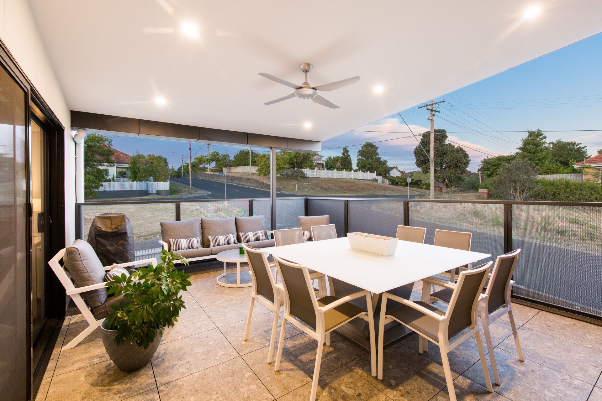Covered outdoor patio with dining table, chairs, lounge seating, and potted plants at sunset — Jetsonian Constructions In Wendouree, VIC