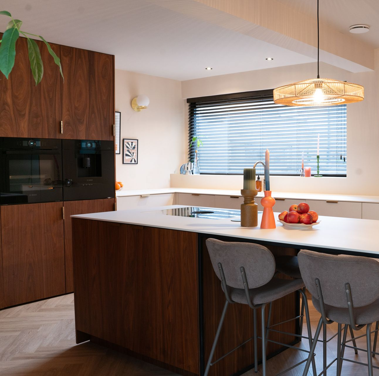 Moderne keuken met een houten kookeiland, witte werkbladen en barkrukken.