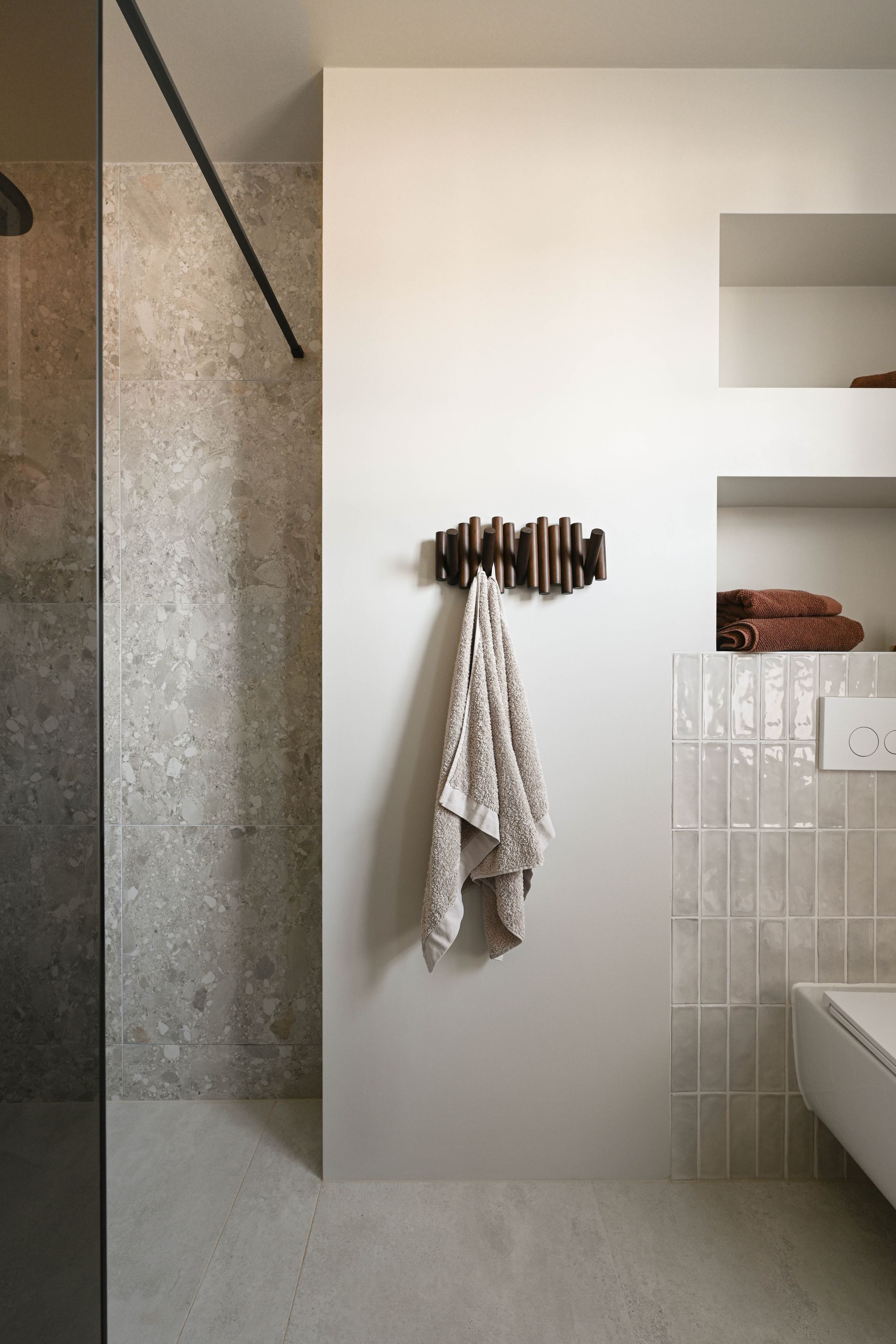 Moderne badkamer met een handdoek die aan een decoratieve houder hangt; neutrale kleuren, ingebouwde planken.