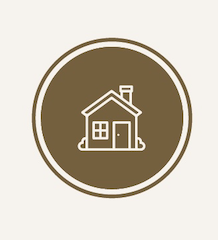 Bruin, rond pictogram met een witte omlijning van een huis, dat onroerend goed of een woning symboliseert.