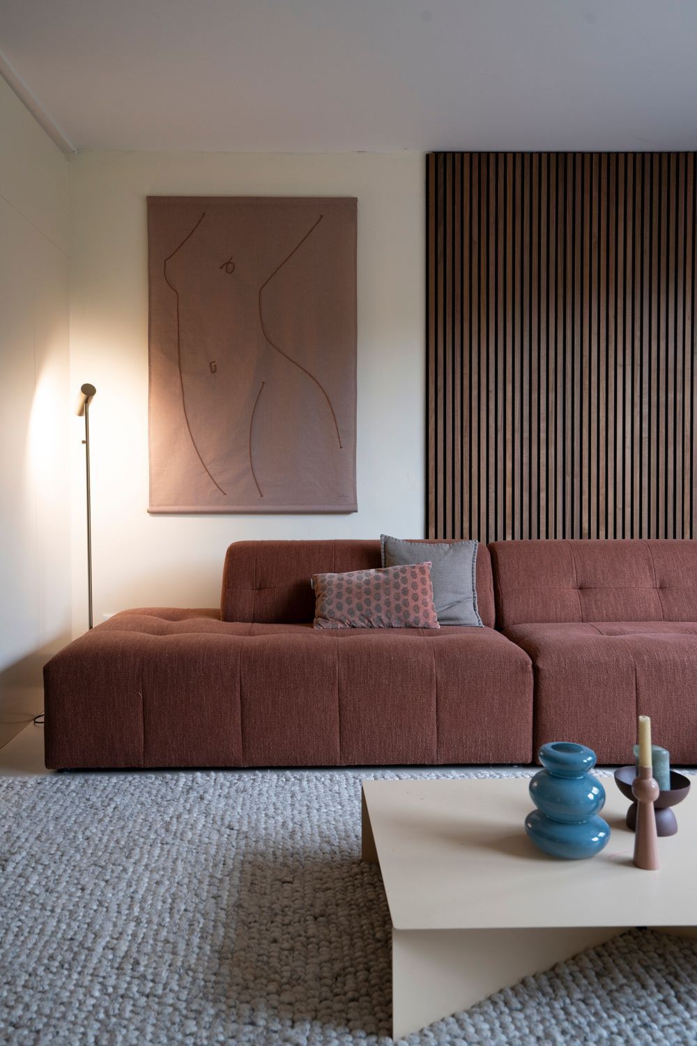 Moderne woonkamer met een bruine hoekbank, kunst en houten lambrisering.