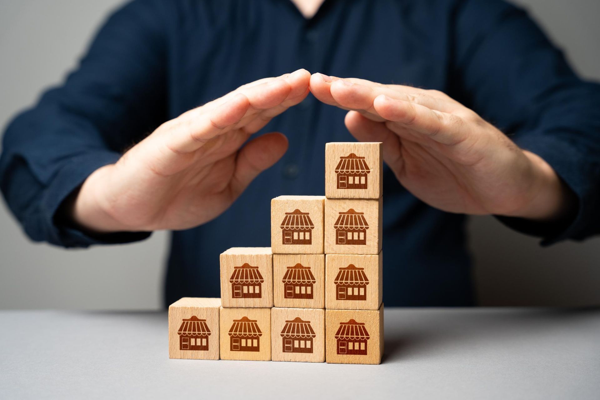 Hands sheltering a staircase of blocks with franchise logos, symbolizing protection and growth.