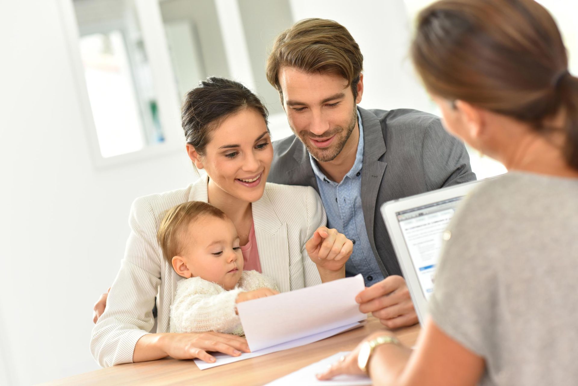 Family with baby at a table reviewing documents with a professional, indoors.