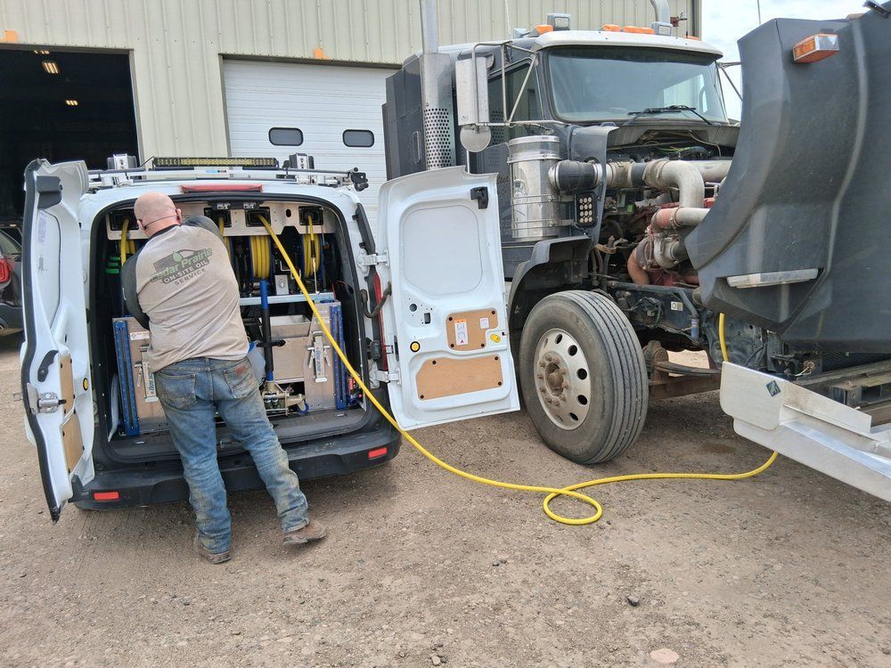Worker using tools beside a white van and semi-truck at an industrial site