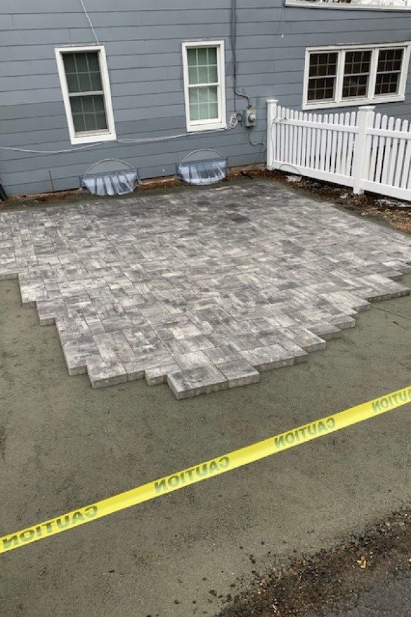 A brick patio is being built in front of a house.