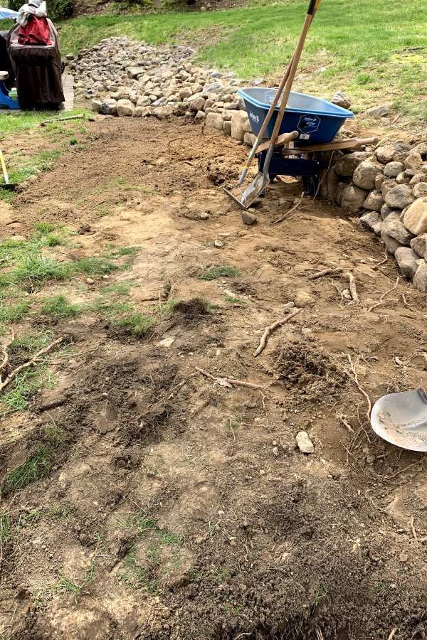 A wheelbarrow is sitting on top of a pile of dirt in a yard.