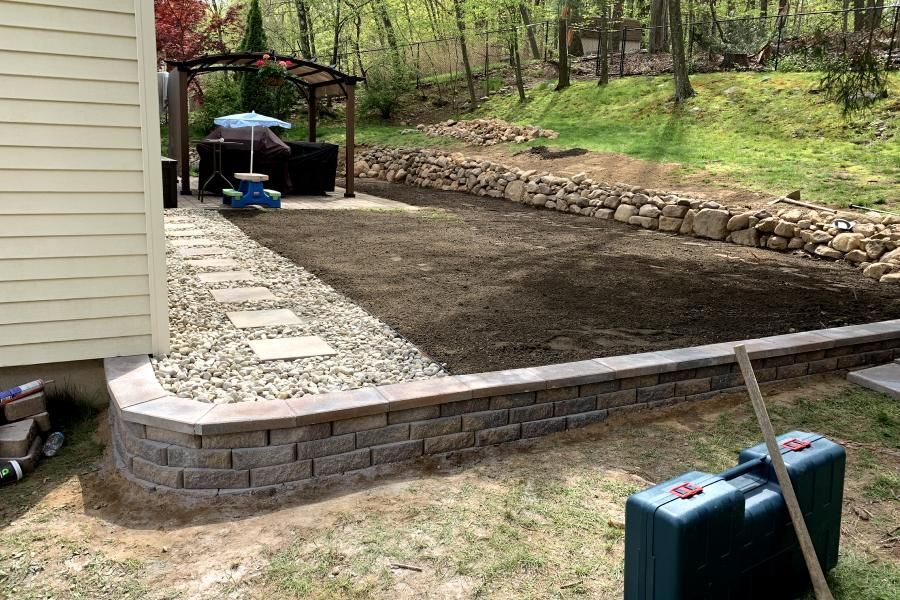 A brick wall is being built in the backyard of a house.