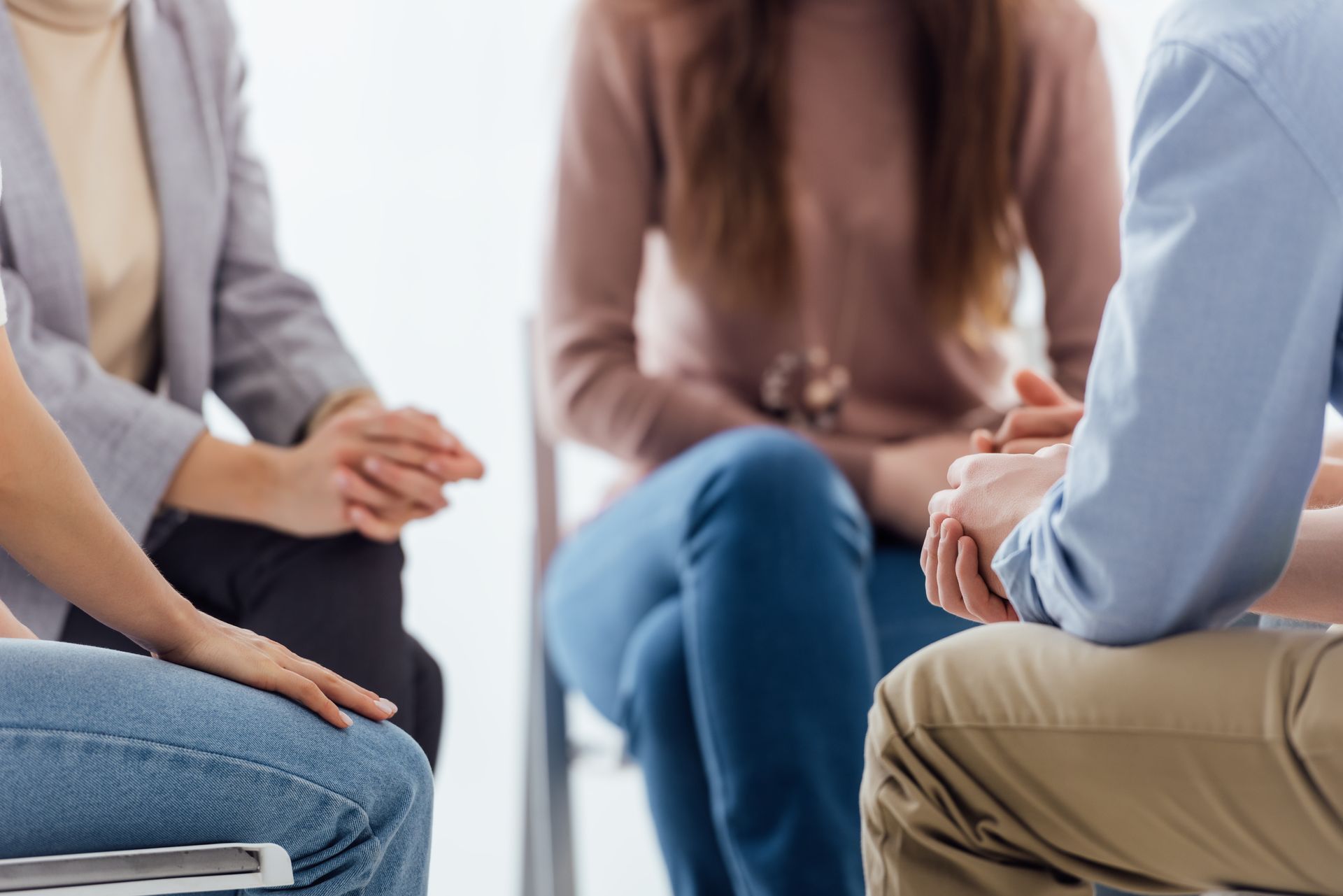 Small group seated in a circle, hands clasped, in a counseling or discussion session Small group seated in a circle, hands clasped, in a counseling or discussion session