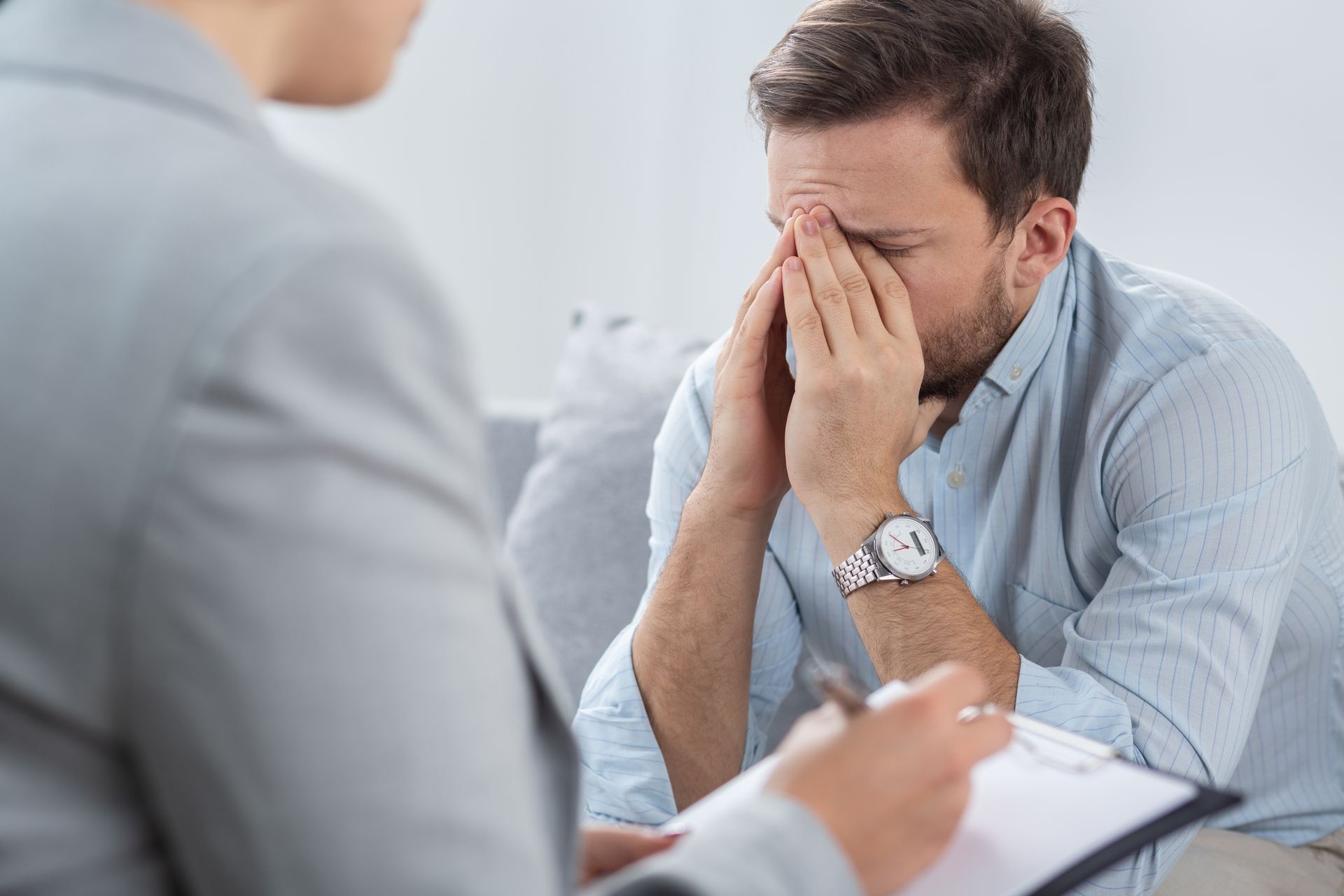 Stressed man sitting with head in hands during a counseling session