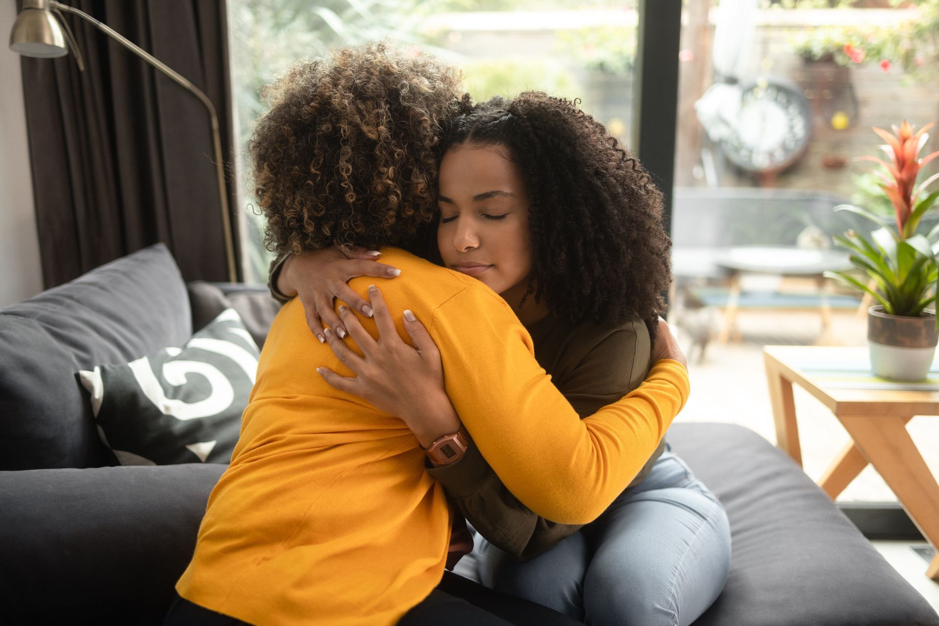 Two people hugging on a couch in a bright living room