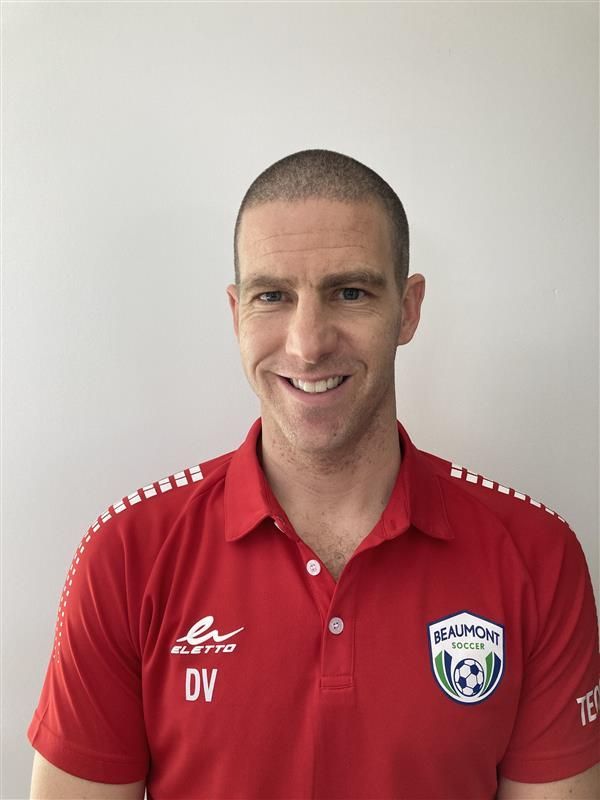Man in red polo shirt with logo, smiling against a plain light background