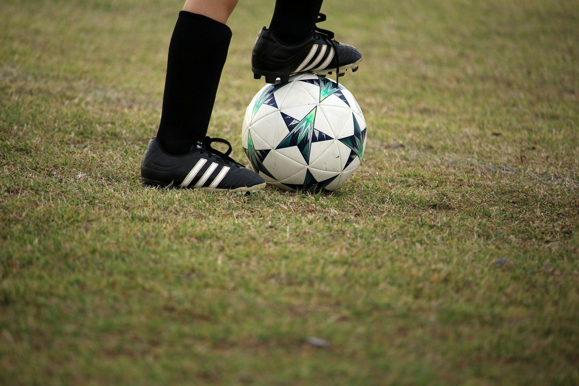 Soccer player’s feet poised on a ball on a grassy field