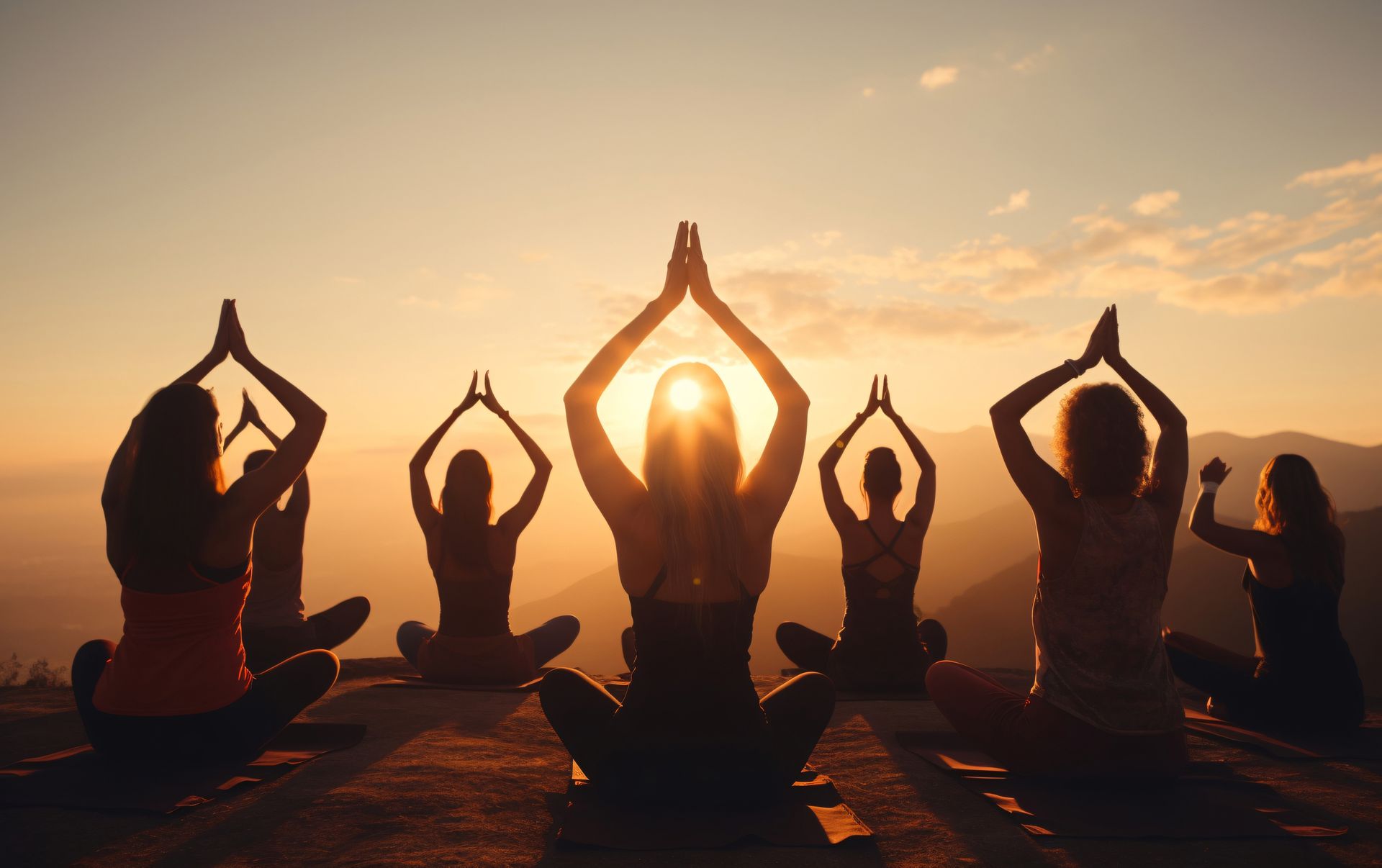 Siluetas de personas practicando yoga al amanecer en un mirador de montaña