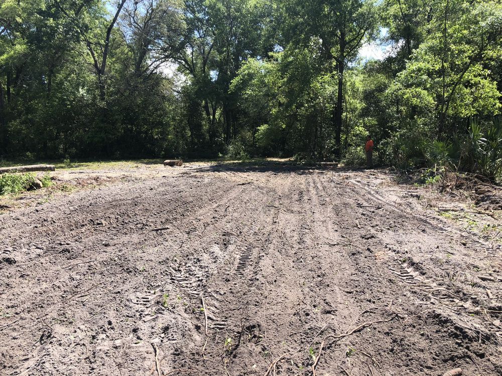 A muddy field with trees in the background.