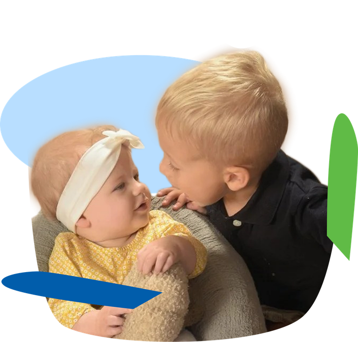 Two young children leaning close, one touching the other’s face, with colorful abstract shapes behind them
