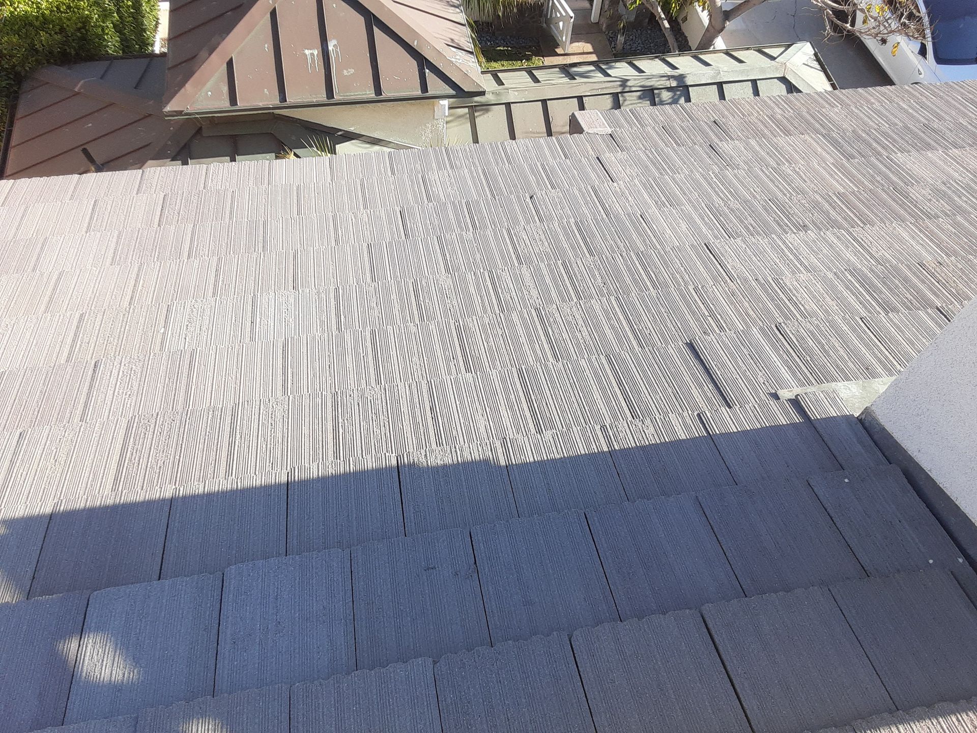 Gray tiled rooftop with steps leading up, houses in background.
