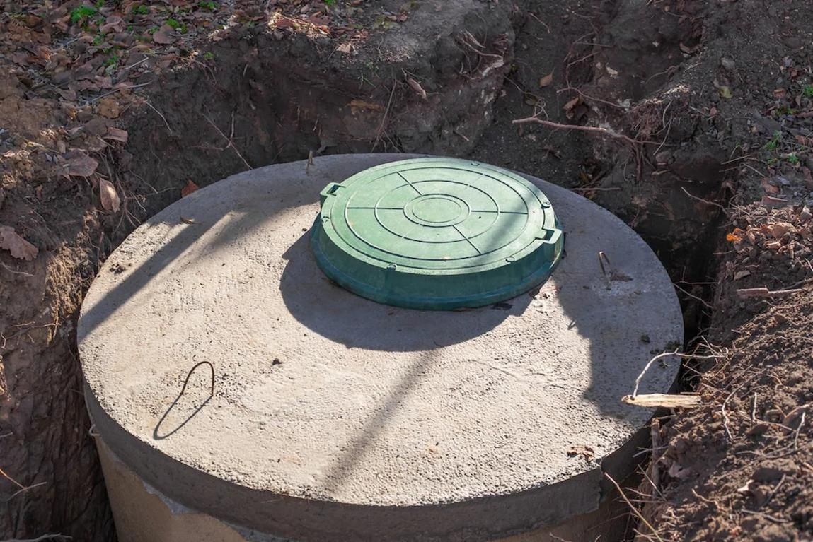 A Concrete Septic Tank With a Green Lid is Sitting in the Dirt — Mid Coast Liquid Waste In Taree, NSW