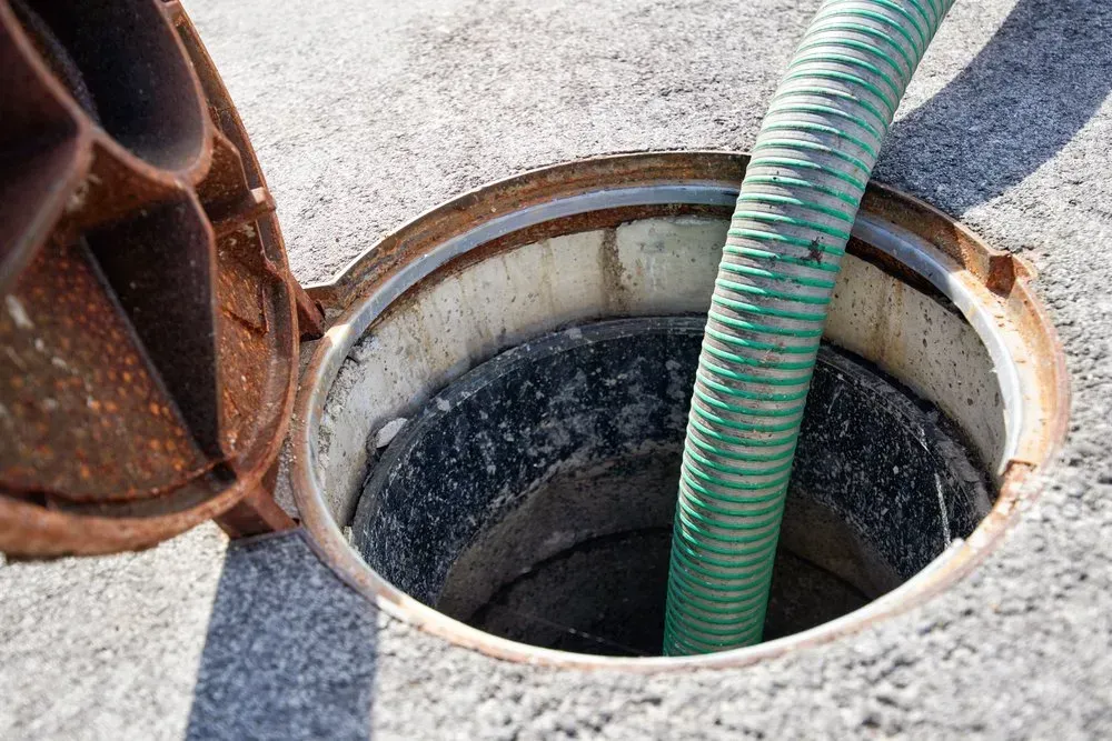 A Green Hose is Coming Out of a Manhole Cover — Mid Coast Liquid Waste In Rainbow Flat, NSW