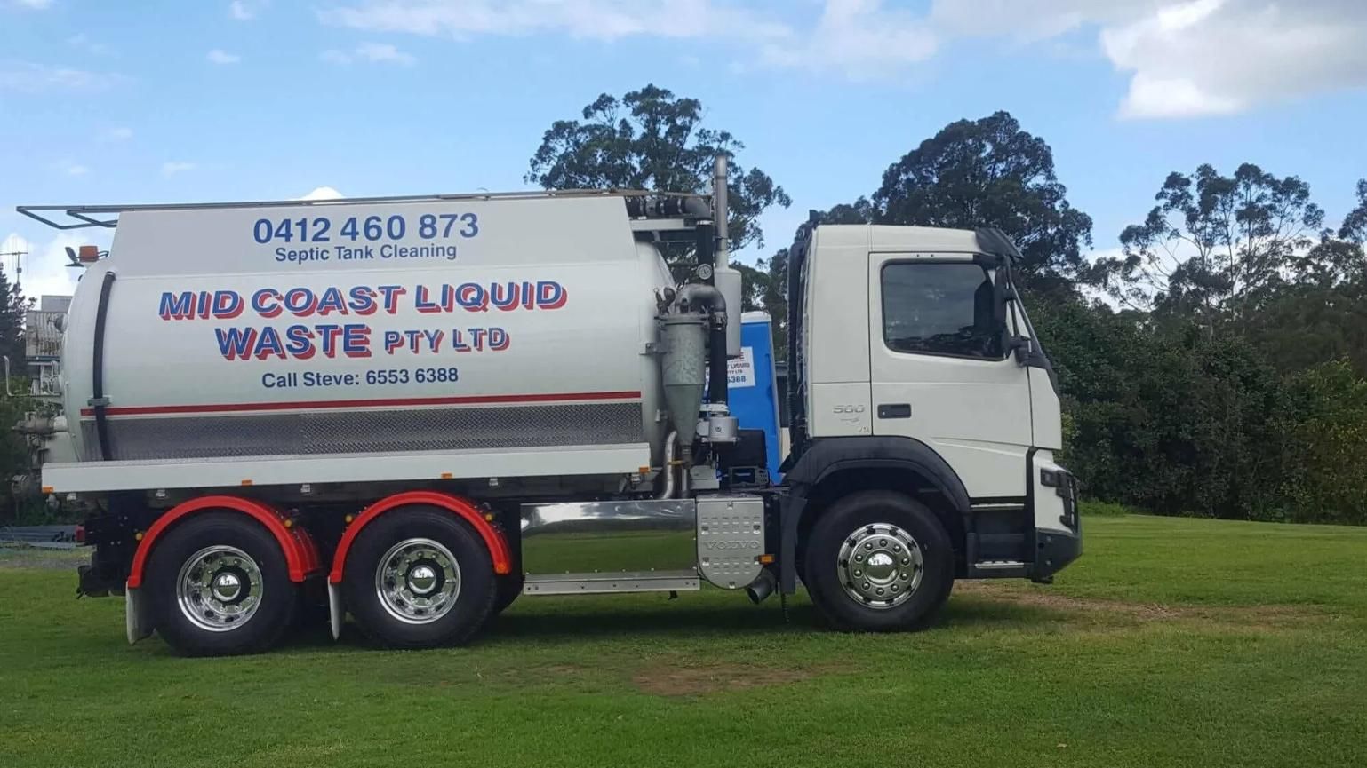 A White Waste Truck is Parked in a Grassy Field — Mid Coast Liquid Waste In Gloucester, NSW