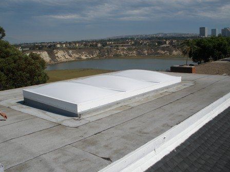 White, arched skylight on a flat roof overlooking a bay and city buildings.