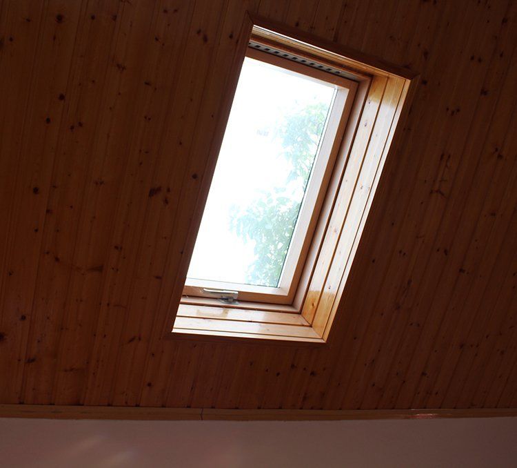Skylight in a wood-paneled ceiling, angled view from below, showing the outdoors.