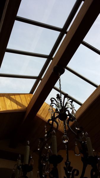 Skylight with wooden beams and a chandelier hanging below, visible against the cloudy sky.