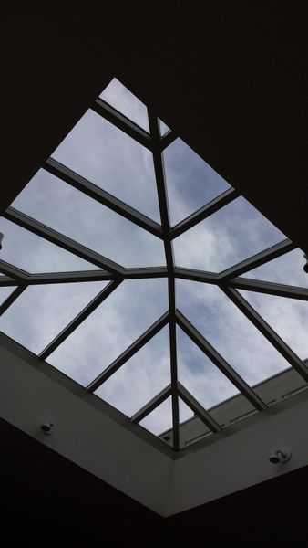 Skylight with geometric metal frame against a cloudy sky.