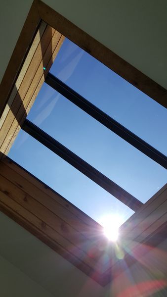 Skylight framing a bright blue sky with the sun shining, creating lens flare.