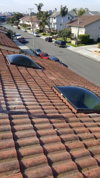 Terracotta tile roof with two skylights, overlooking a street with parked cars and houses.