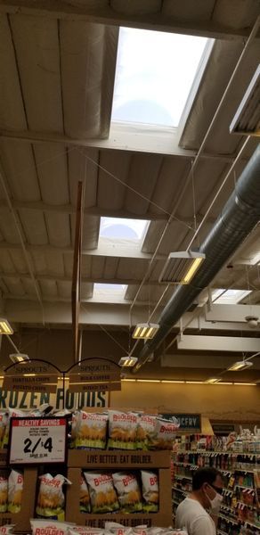 Grocery store interior with skylights in the ceiling and produce on display.