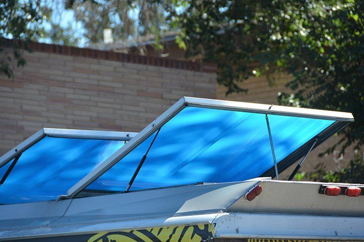 Blue awning sections extended from a vehicle roof, with a brick building in the background.