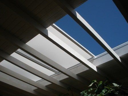 Exterior ceiling with beams and a view of the blue sky through a rectangular opening.