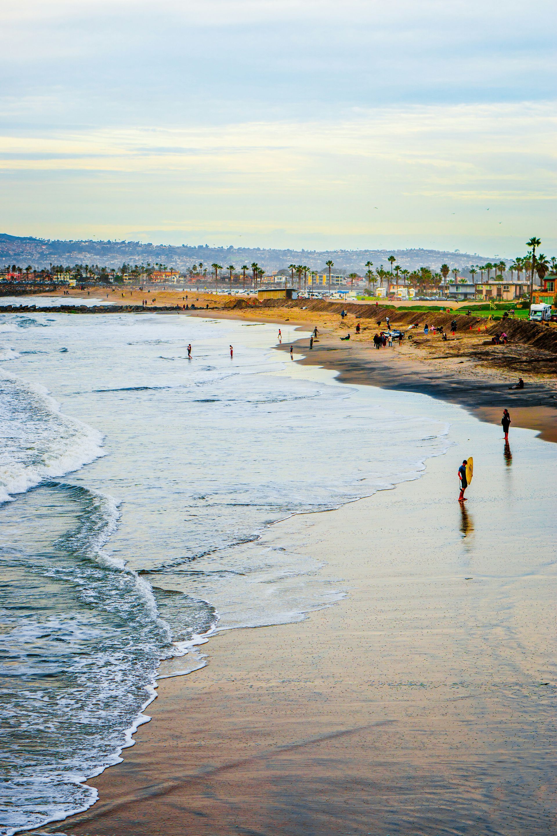 A group of people are walking on a beach near the ocean.