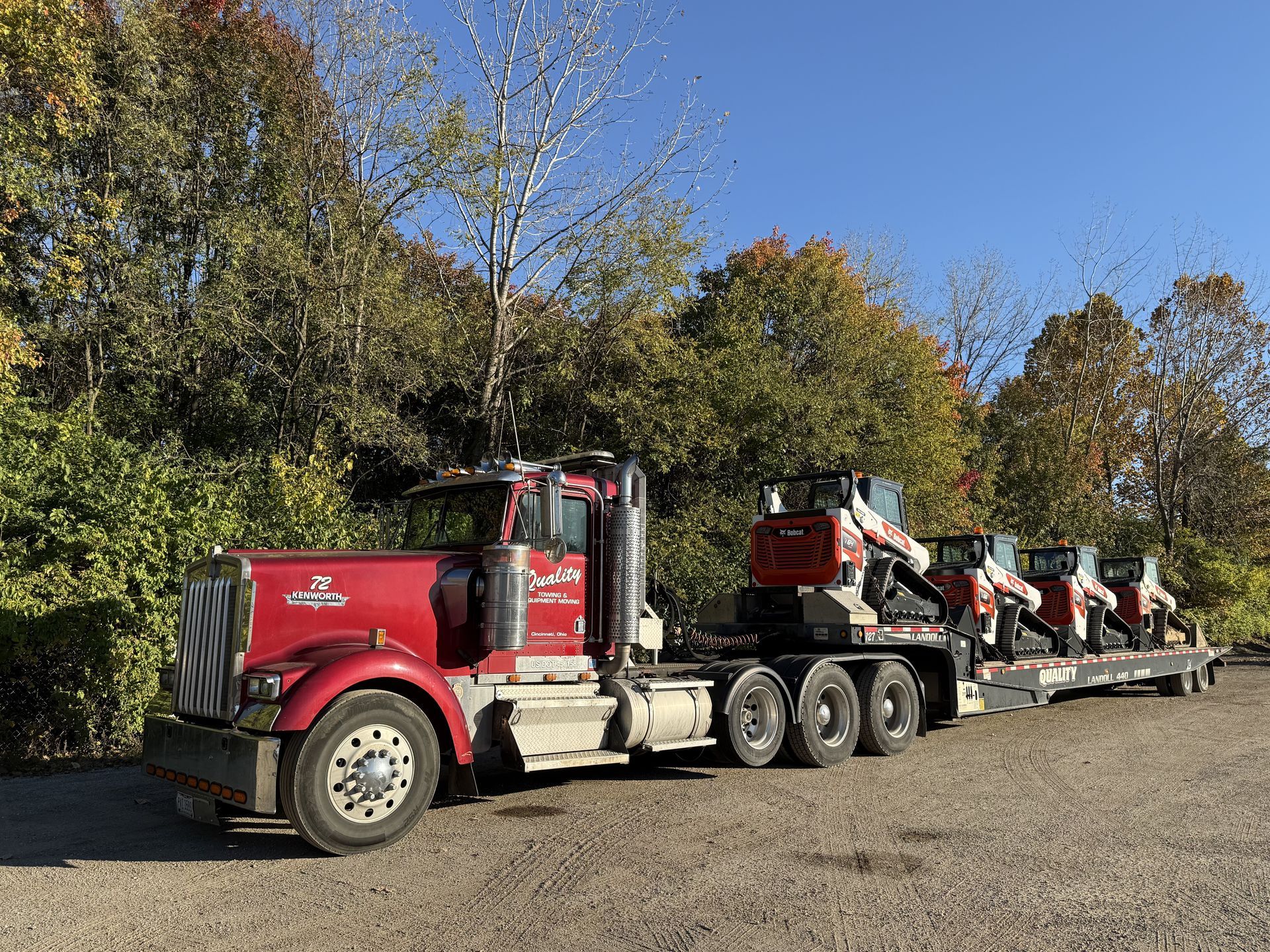 flatbed semi-truck hauling four skid steer loaders