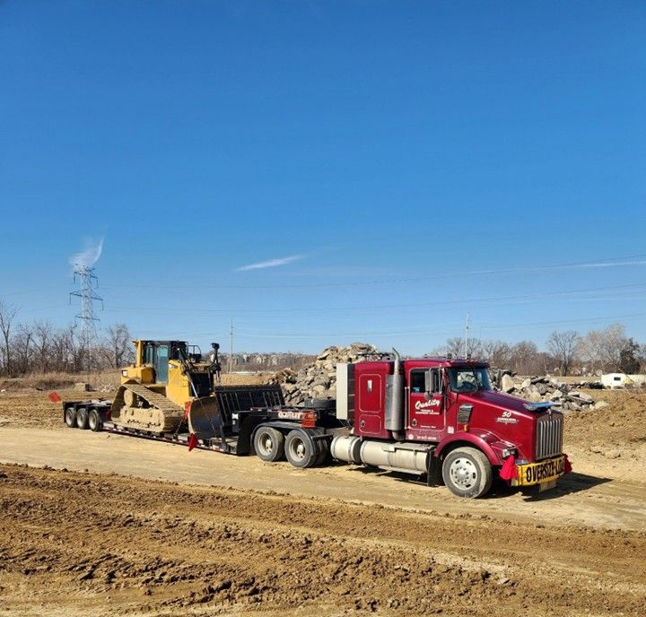 Truck hauling large yellow machinery off-road under a blue sky. Truck hauling large yellow machinery off-road under a blue sky.