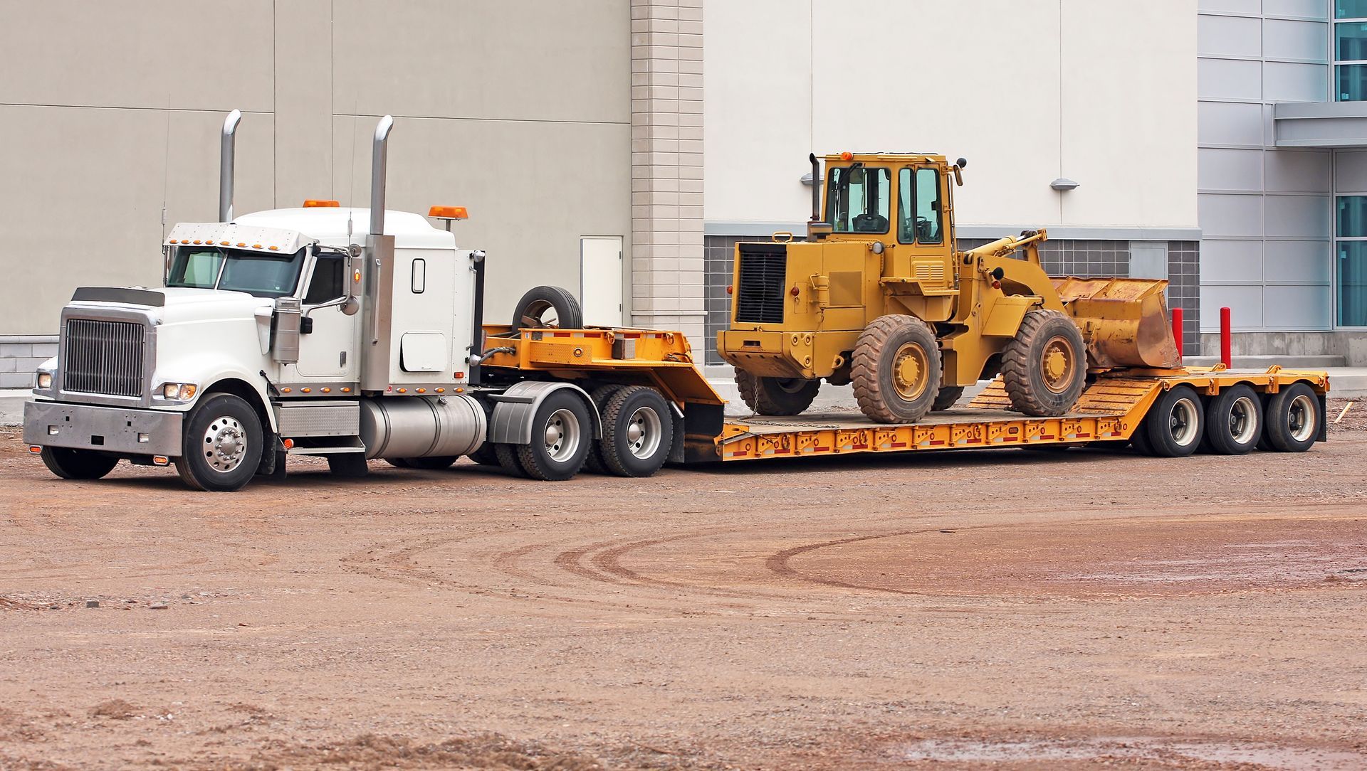 A truck is transporting a pay loader.