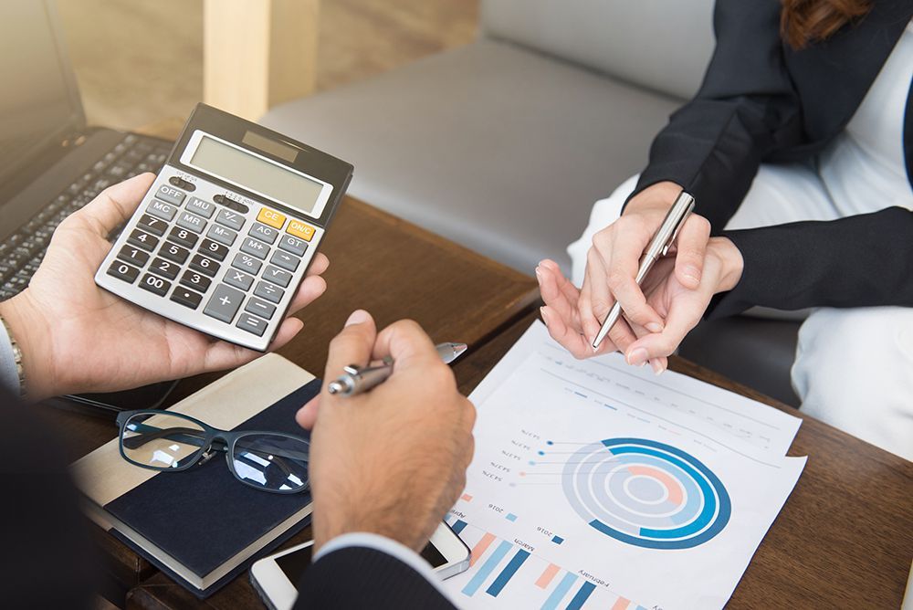 a man is holding a calculator and a woman is writing on a piece of paper